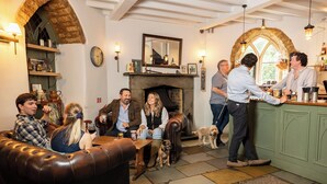 Un pub chaleureux avec une cheminée, des fauteuils en cuir et un coin bar.