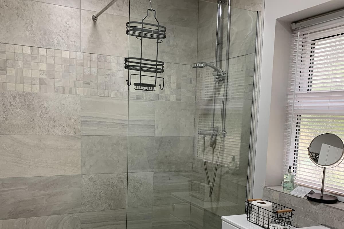 Un baño moderno con ducha de vidrio, inodoro y lavamanos.