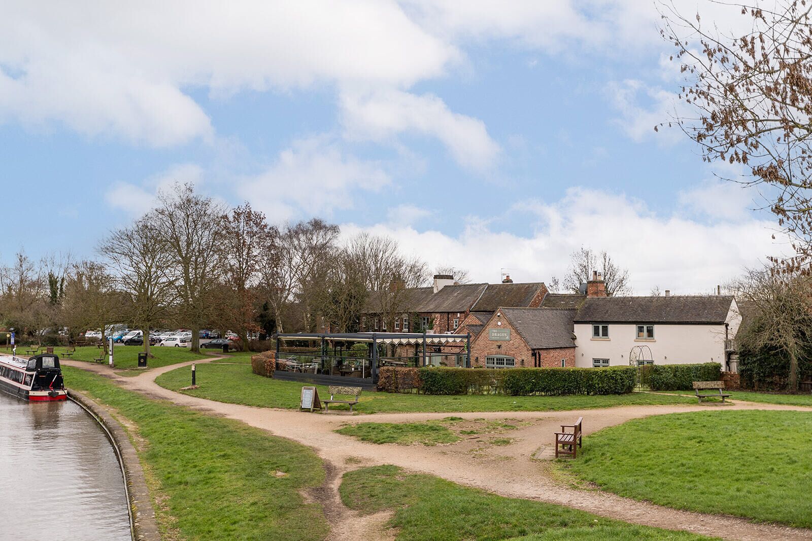 A riverside view with a pub named 'Dragon' and a boat docked by the water.