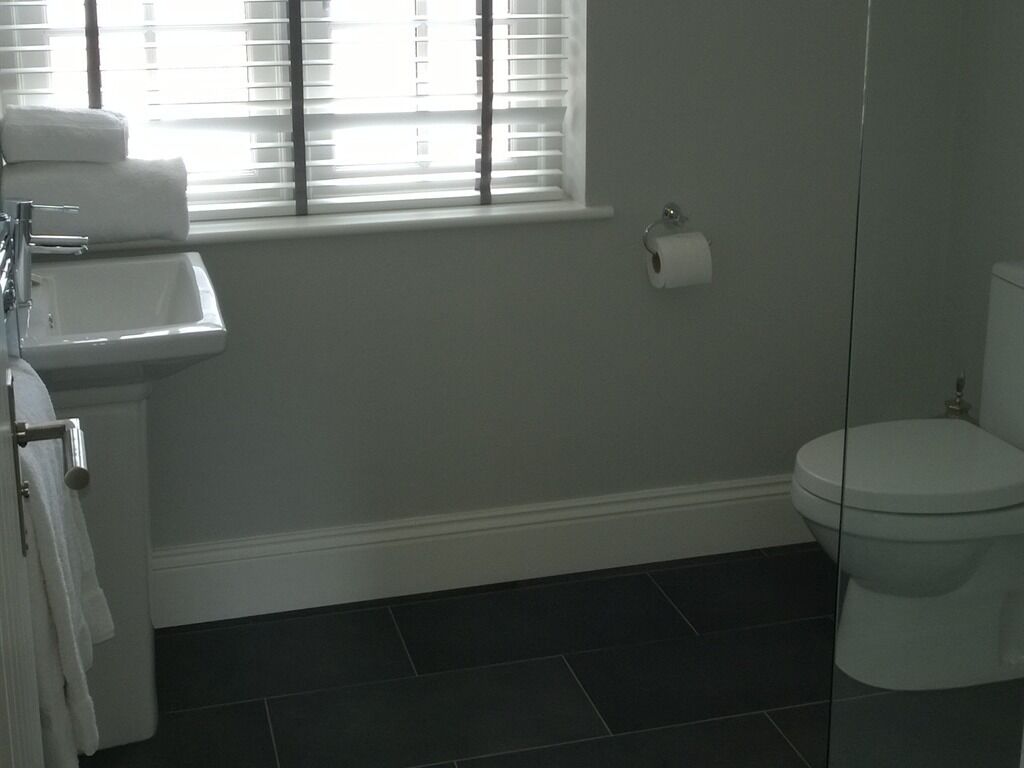 A bathroom with a sink, toilet, and window with blinds.
