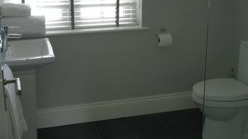 A bathroom with a sink, toilet, and window with blinds.