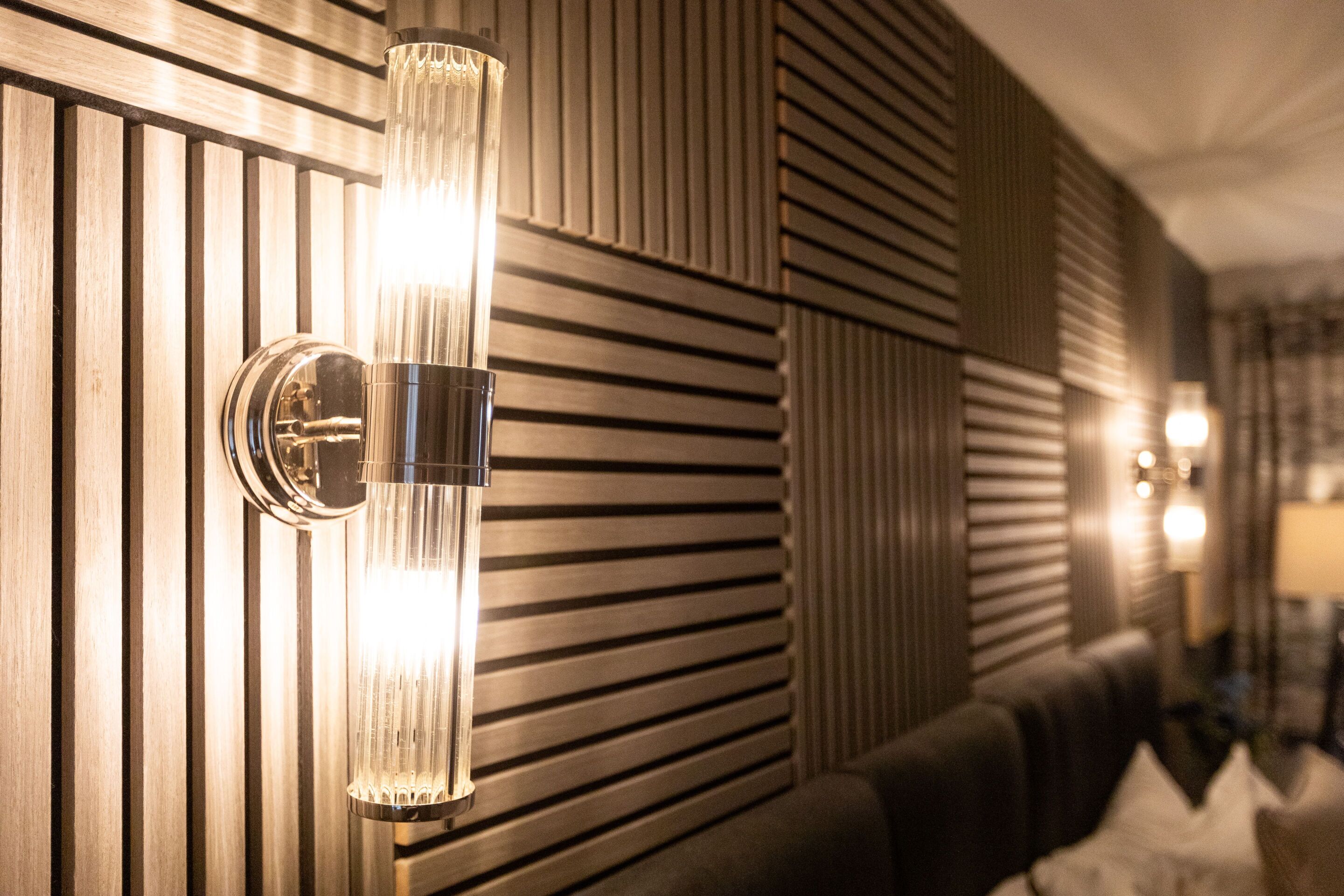 Et moderne interiør med en vægmonteret lampe og et mønstret vægdesign.