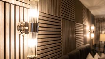 Et moderne interiør med en vægmonteret lampe og et mønstret vægdesign.