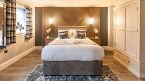 A modern bedroom with a large bed, wooden panel wall, bedside tables, and a wardrobe. - The Dragon (Derby)