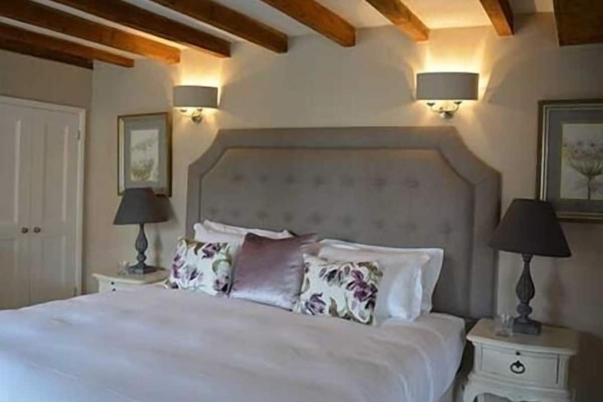 Un dormitorio con una cama grande, dos mesitas de noche con lámparas y un techo de madera.
