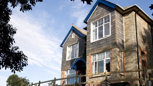 A two-story house with a gabled roof, a front porch, and a visible garage. - Boscastle House (Boscastle)