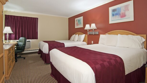 A hotel room with two beds, a desk, a chair, and two wall-mounted lamps. - Valley Inn Shakopee (Shakopee)