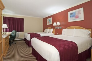 Ein Hotelzimmer mit zwei Betten, einem Schreibtisch, einem Stuhl und zwei Wandlampen.