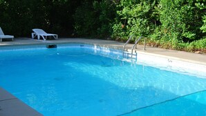 A swimming pool with a 4 ft depth marker, surrounded by white lounge chairs and a metal ladder. - RoseWood Inn (Bryson City)