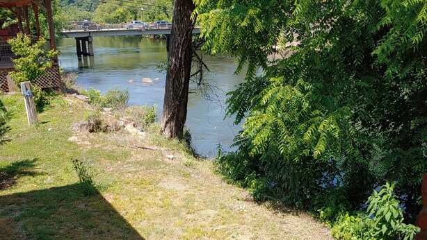 A riverside view with a wooden deck, a gazebo, and a bridge in the background. - RoseWood Inn (Bryson City)