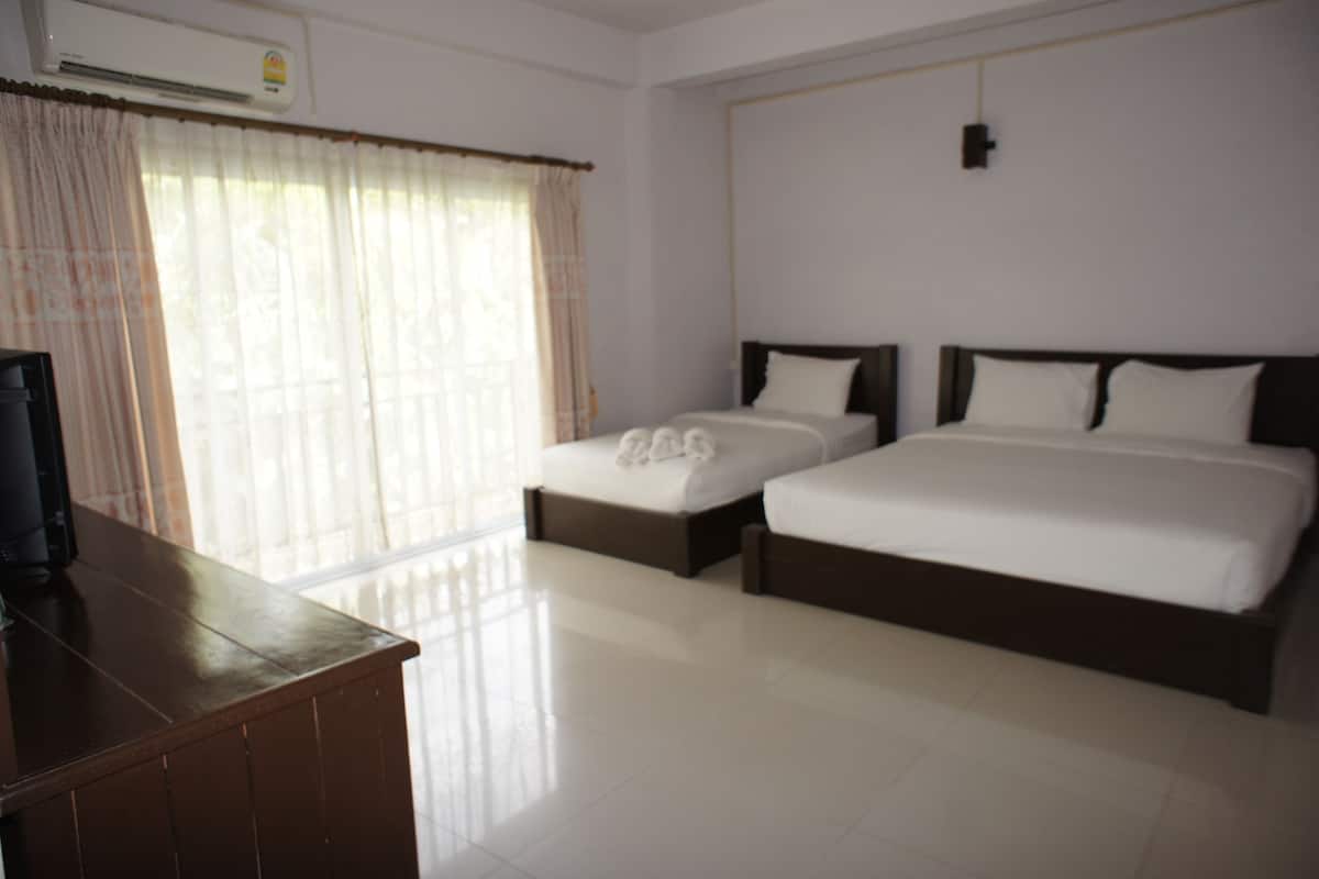A hotel room with two beds, a wooden desk, and a large window with curtains.