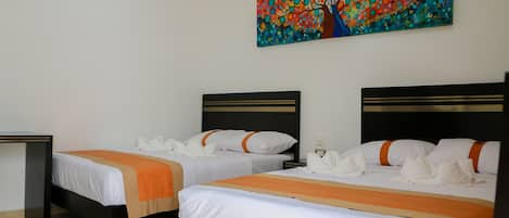 Habitación de hotel con dos camas, cada una con ropa de cama blanca y detalles en naranja, una mesita de noche y un cuadro abstracto colorido en la pared.
