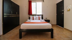 A hotel room with a bed, a nightstand, a wardrobe, and a window with a red curtain. - Gayser Apartamentos (Valladolid)