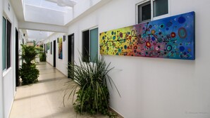 A corridor with a skylight, a colorful abstract painting, and potted plants. - Gayser Apartamentos (Valladolid)