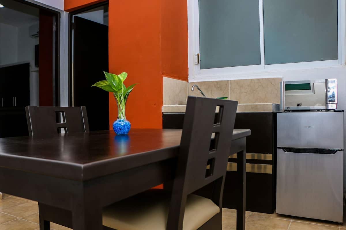 A modern kitchen with a dining table, chairs, a refrigerator, and a potted plant.