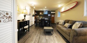 A cozy living room with a sofa, a dining table, and a kitchen area in the background. - Private Vacation Villa Kohola (Motobu)