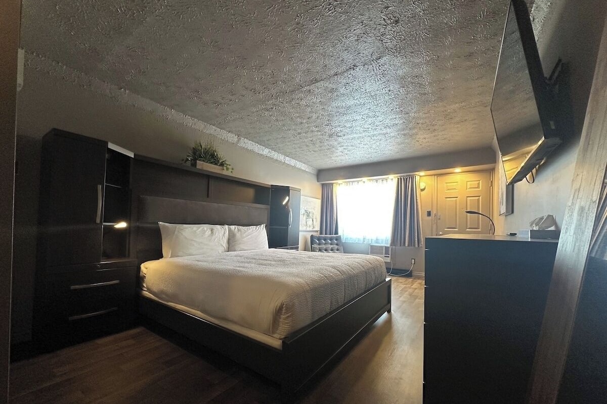 Un dormitorio con cama, mesitas de noche, armario y escritorio.
