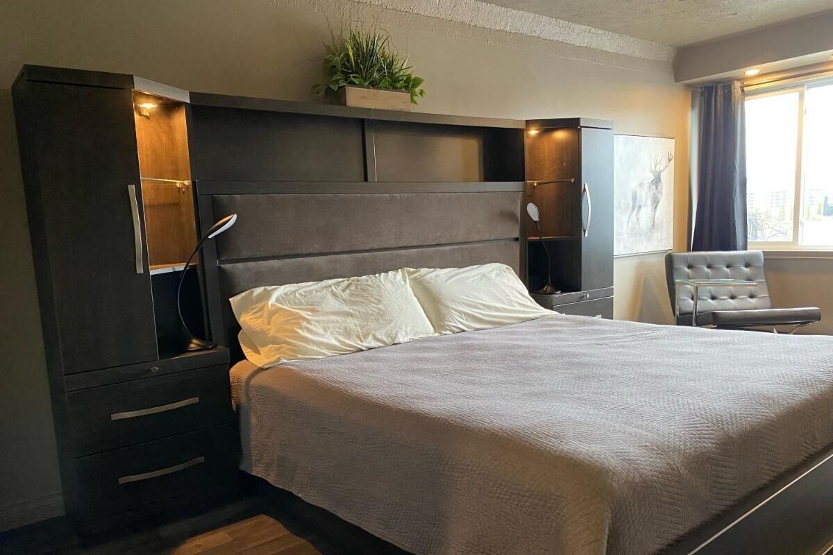 Un dormitorio moderno con una cama grande, mesitas de noche, un armario y una ventana con cortinas.