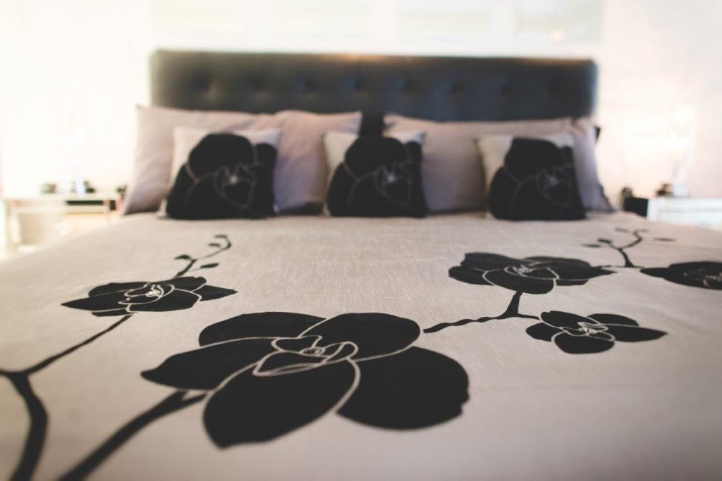 A bed with a floral bedspread, a dark headboard, and white pillows.