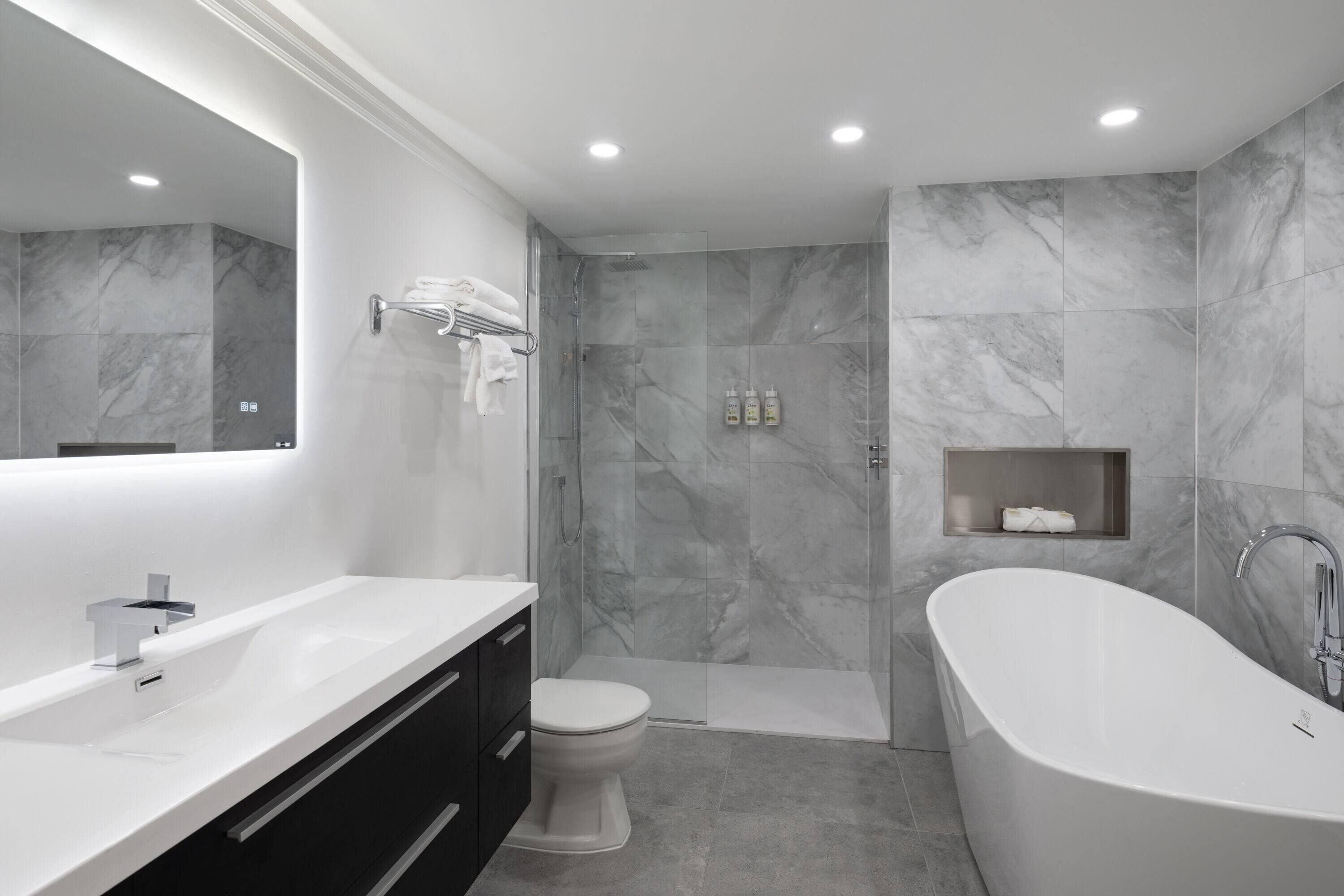 Een moderne badkamer met een vrijstaand bad, toilet en douche.