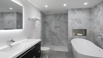 A modern bathroom with a freestanding bathtub, a toilet, and a shower area.