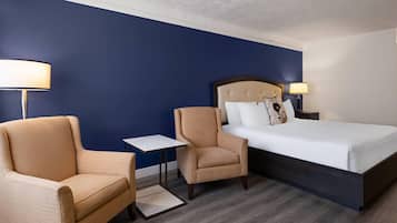 A hotel room with a bed, two armchairs, a small table, and two bedside lamps.