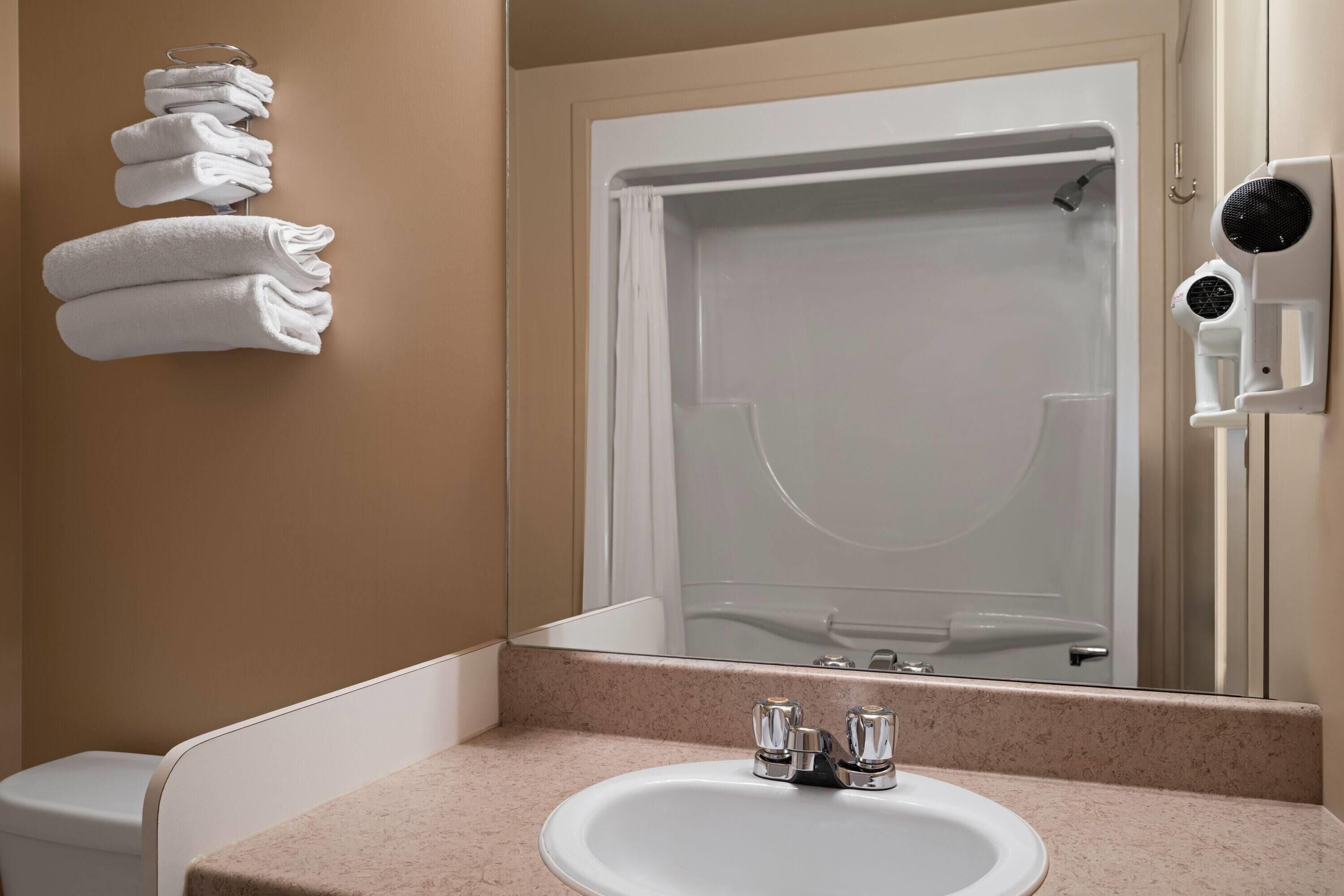 A bathroom with a sink, a mirror, a towel rack, and a shower.