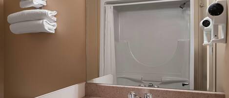 A bathroom with a sink, a mirror, a towel rack, and a shower.