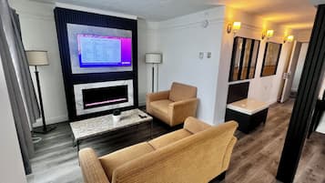 En moderne stue med et fladskærms TV, en pejs, en sofa, et sofabord og en lille plante.