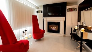 Un salon moderne avec une cheminée, des fauteuils rouges et un téléviseur.
