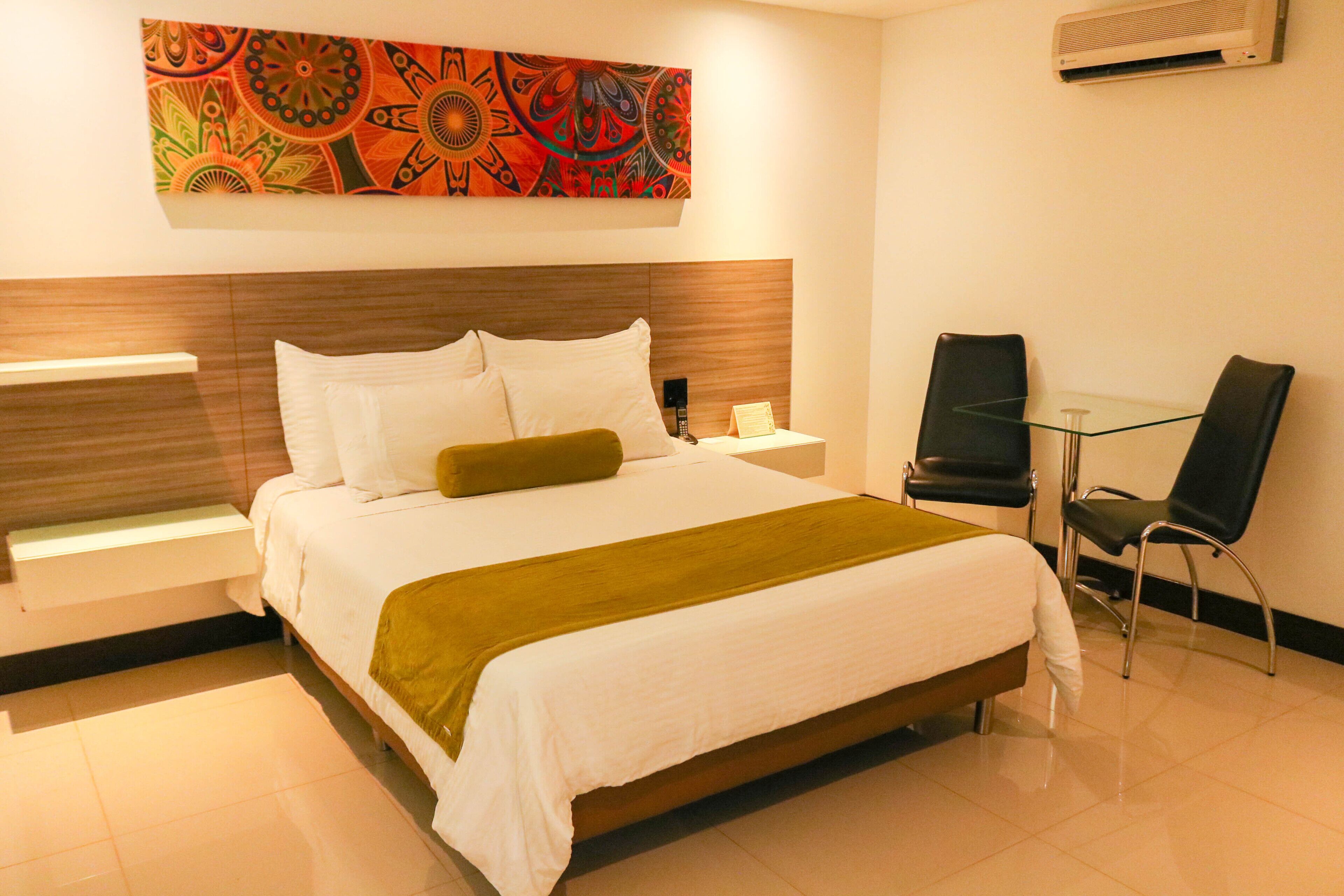 Una habitación de hotel con una cama, un escritorio, una silla y un aire acondicionado instalado en la pared.