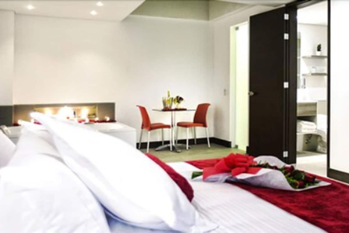 A hotel room with two beds, a dining area with a table and chairs, and a sliding door leading to a closet.