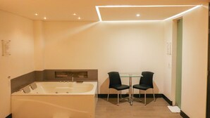Un baño moderno con una bañera grande, dos sillones y una mesita.