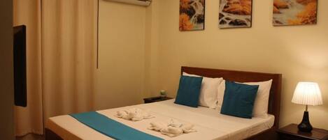 A hotel room with a bed, a nightstand, a lamp, and three paintings on the wall.