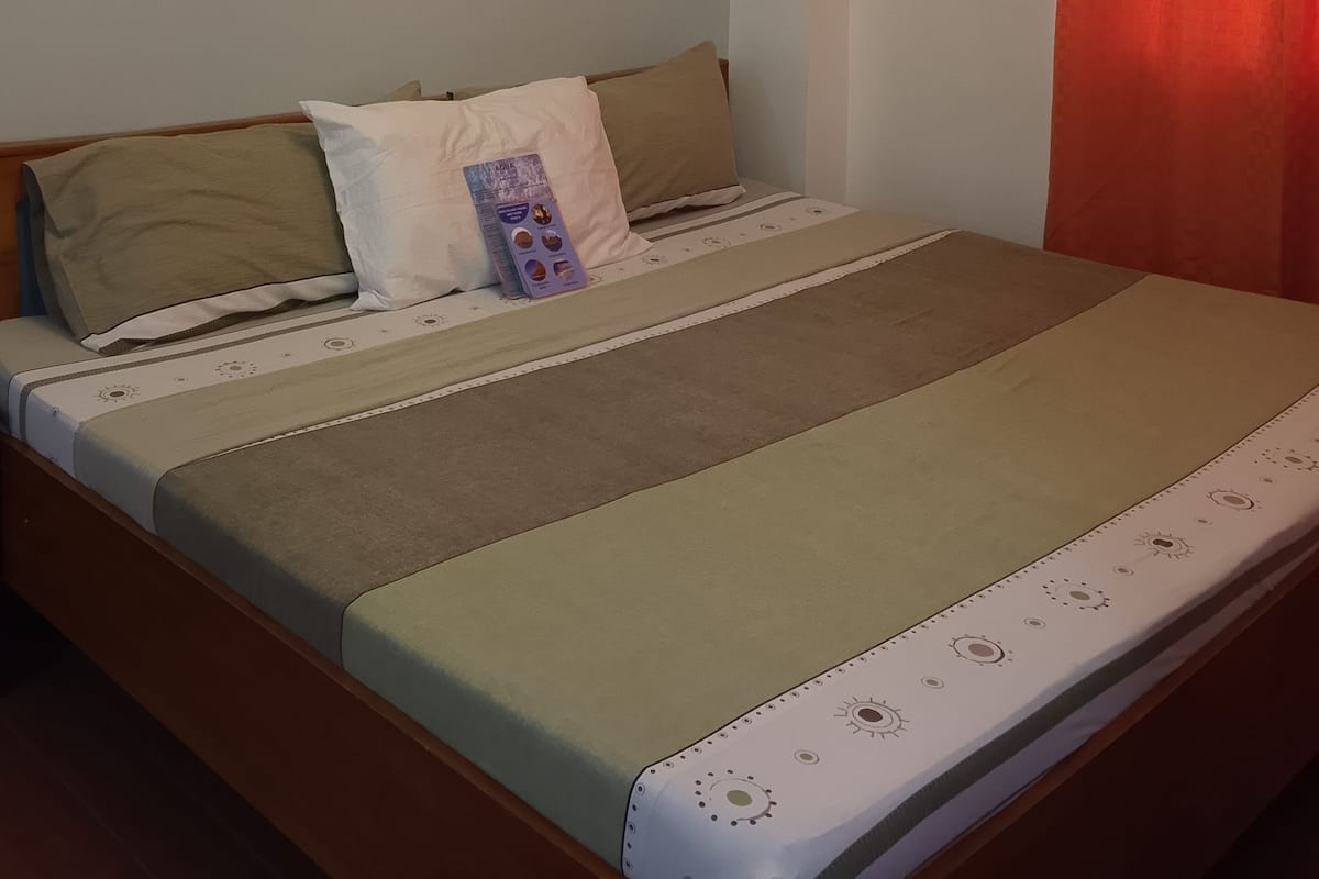 Ein Schlafzimmer mit einem Bett, Kissen, einer Wand-Klimaanlage und einem Gemälde.