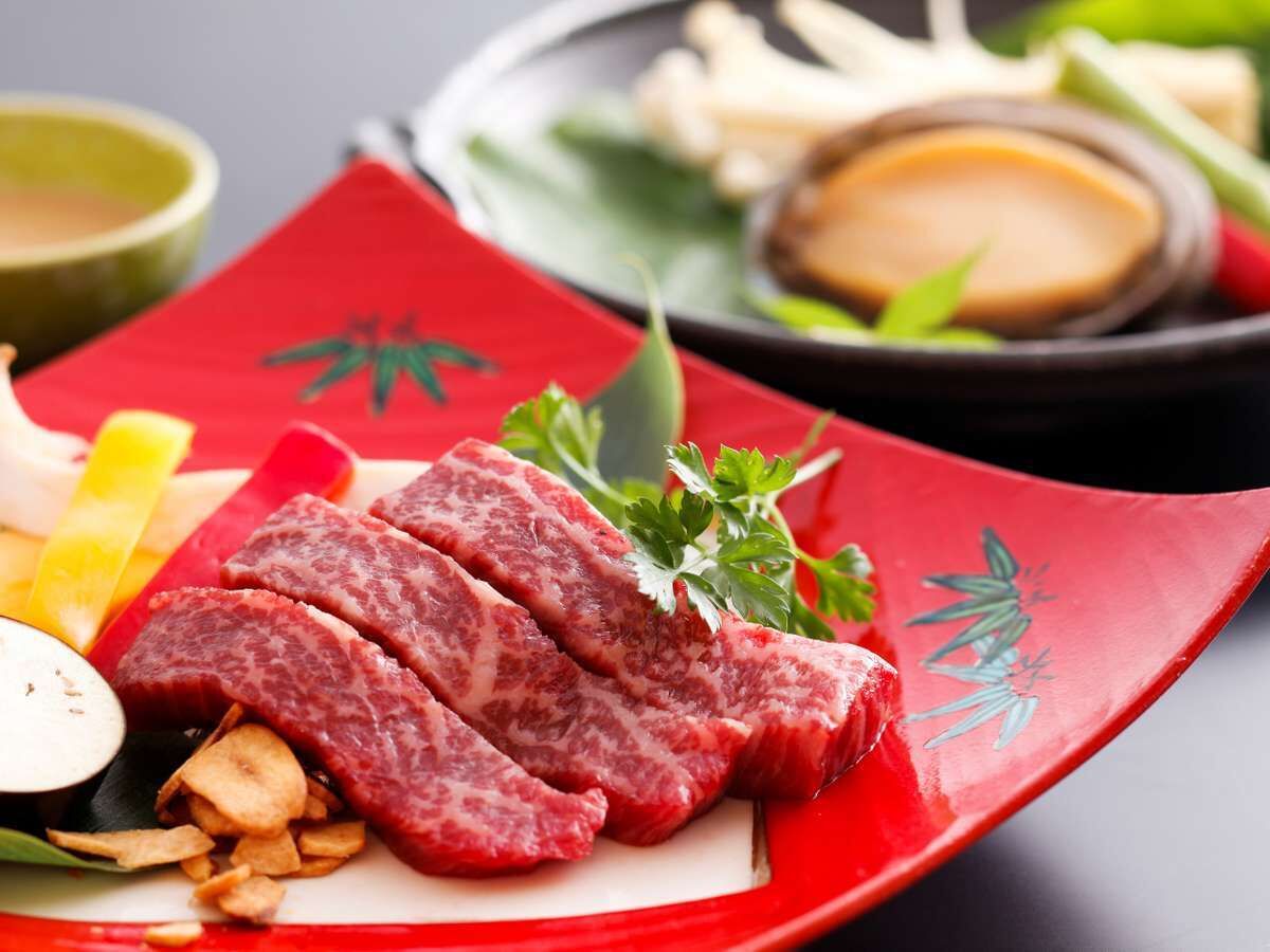 A plate of sliced beef with vegetables and a red napkin.