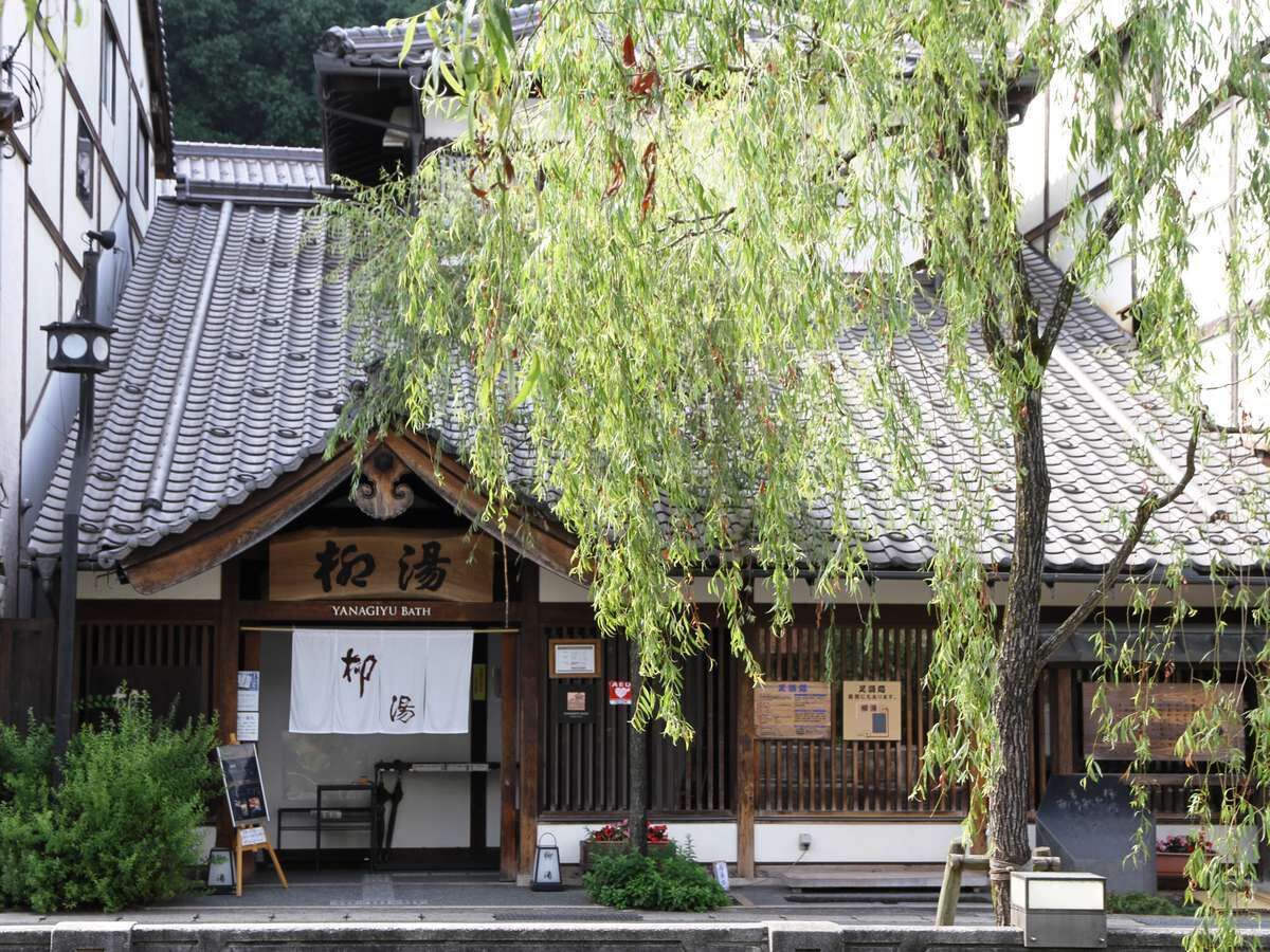 A traditional Japanese building with a tiled roof and a sign reading "YANAGIYU BATH".