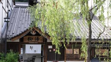 A traditional Japanese building with a tiled roof and a sign reading "YANAGIYU BATH".