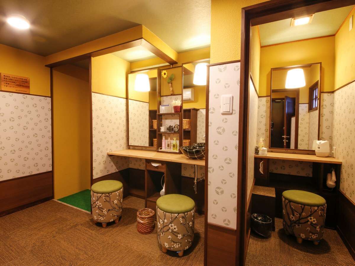 Ein kleines, kompaktes Badezimmer mit zwei Hockstühlen, einem Spiegel und einem Ablagebrett mit Toilettenartikeln.