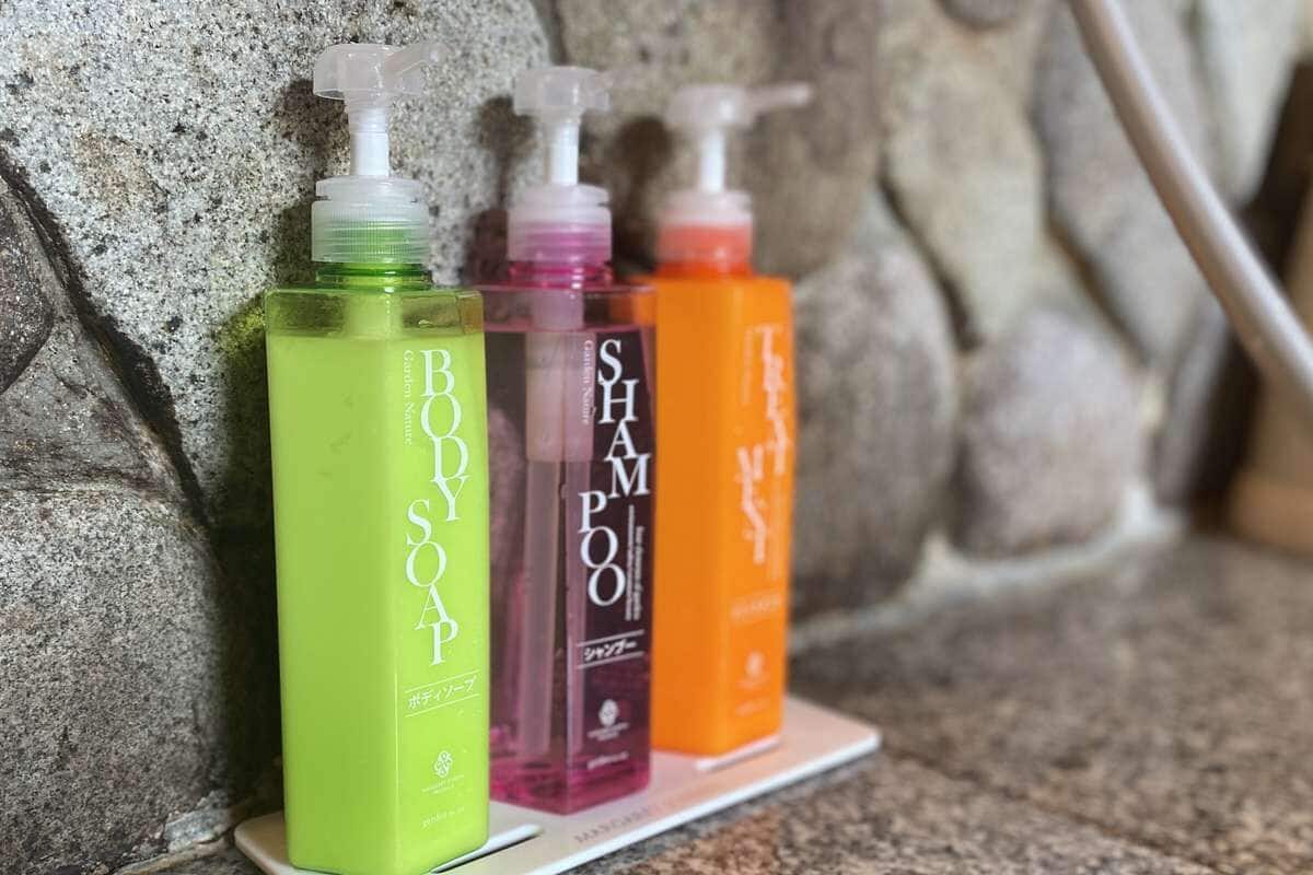 Four bottles of shampoo on a shelf against a stone wall.
