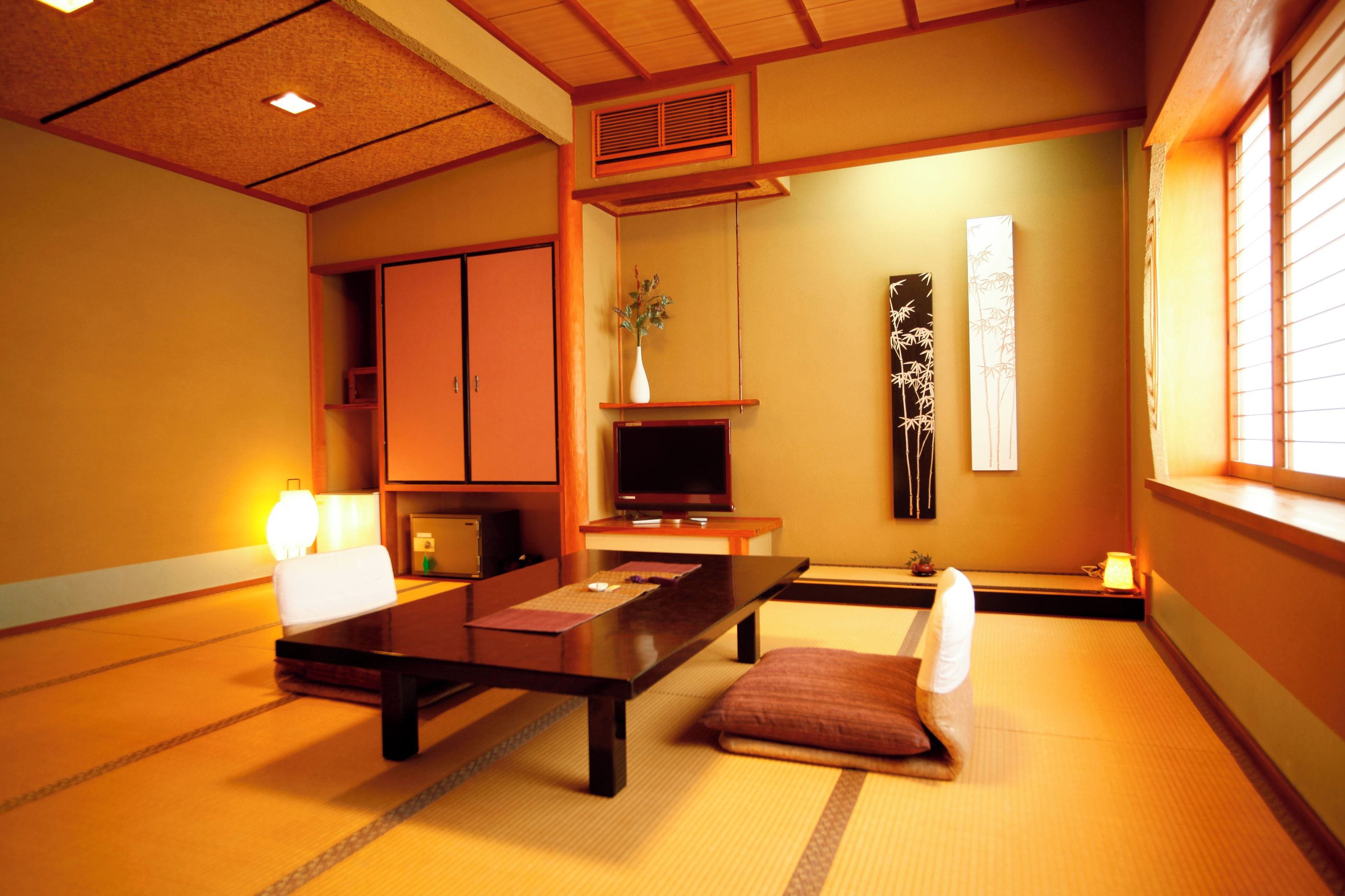 A traditional Japanese-style room with tatami flooring, a low table, a television, and a sliding door.