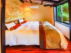 Una camera da letto con un letto, una parete in pietra, una finestra e un condizionatore d'aria.