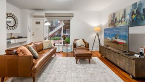 A modern living room with a brown leather sofa, a glass coffee table, and a wooden cabinet with a television.