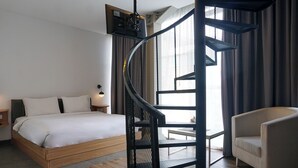 A modern hotel room with a curved staircase, a bed, a chair, and a desk. - 1O1 URBAN Jakarta Glodok - Kota Tua (Jakarta)