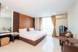A hotel room with a bed, a desk, a chair, a TV, and an air conditioning unit. - Tara Monte Hotel Pratunam (Bangkok)