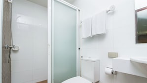A bathroom with a toilet, a shower with a glass door, and a towel rack. - Tara Monte Hotel Pratunam (Bangkok)