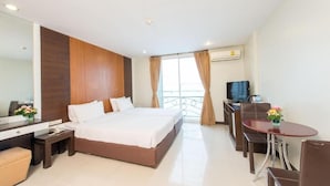 A hotel room with a large bed, a desk with a chair, a small table, a TV, and a balcony with curtains. - Tara Monte Hotel Pratunam (Bangkok)