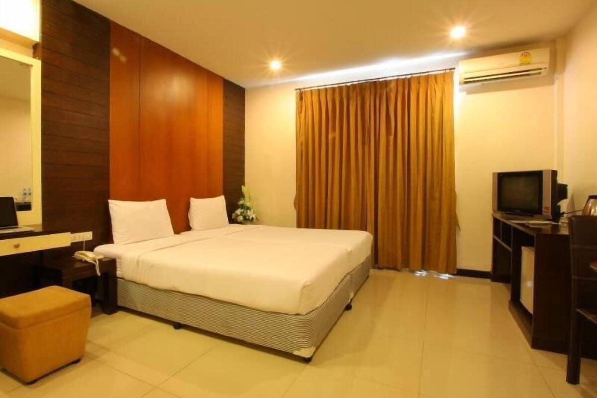 Une chambre d’hôtel avec un grand lit, un bureau avec un ordinateur, une télévision et un appareil de climatisation.