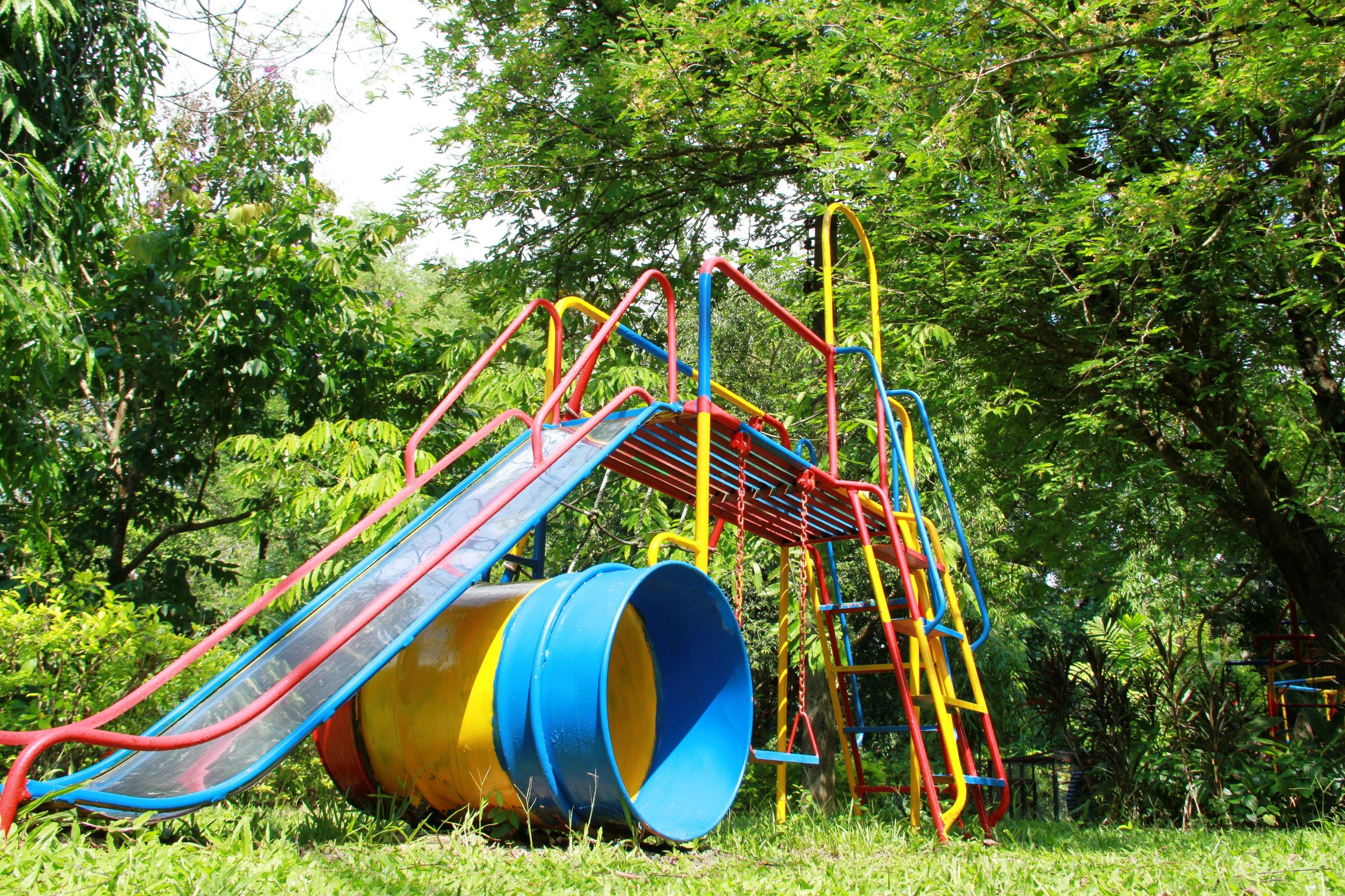 A playground with a slide, climbing structures, and a large cylindrical object.