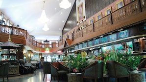 A spacious lobby with a high ceiling, ornate wooden railings, and a variety of seating arrangements including chairs and sofas.